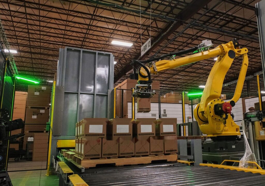 Palletising robot stacking cartons on a pallet on a roller conveyor – palletising station with light curtains